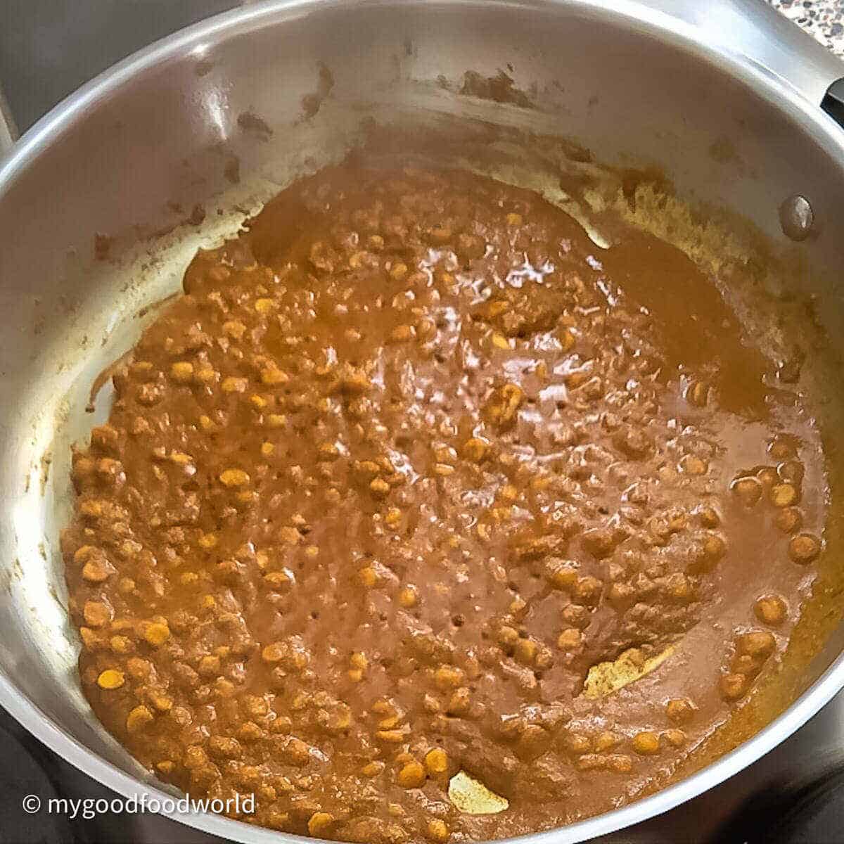 chickpea lentils cooking in spices in a wide pan.