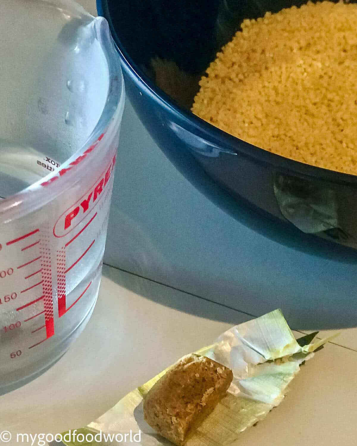 Stock cube, water and couscous placed in bowls on a board.