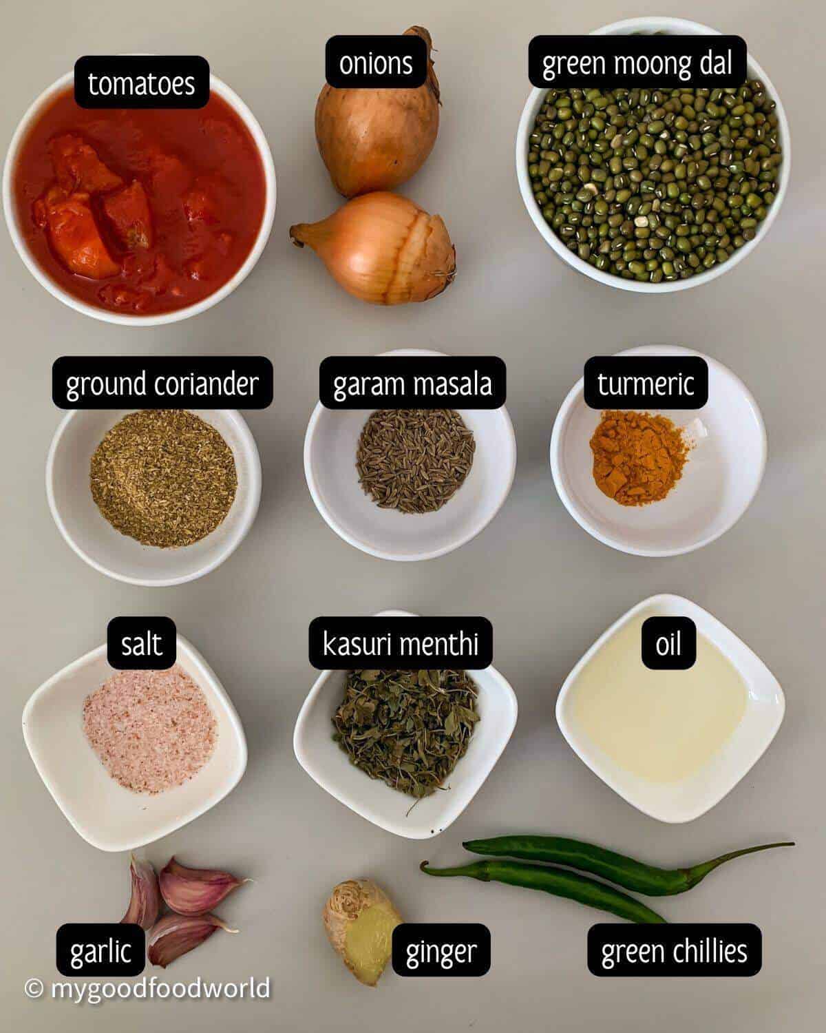 Ingredients for mung dal curry laid out in bowls on a grey mat.