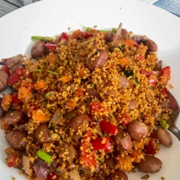 Vegan cous cous salad with beans and vegetables served on a wide bowl.