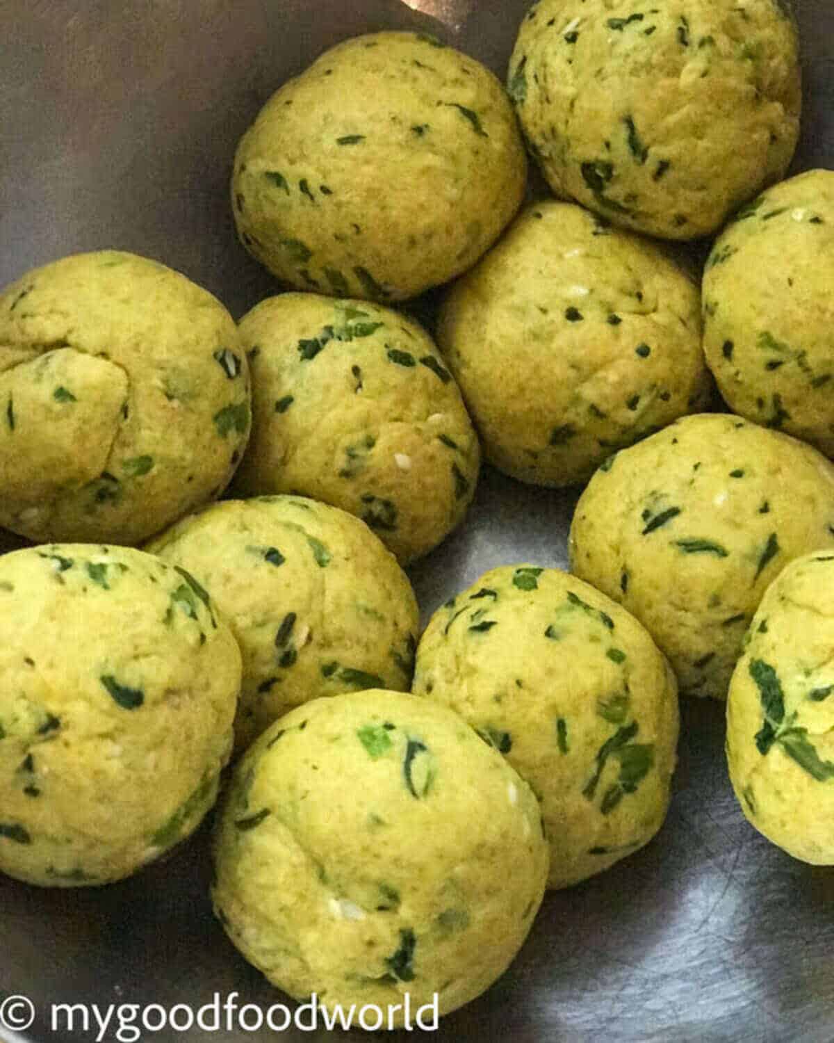 Turmeric roti dough balls placed together on a steel bowl.