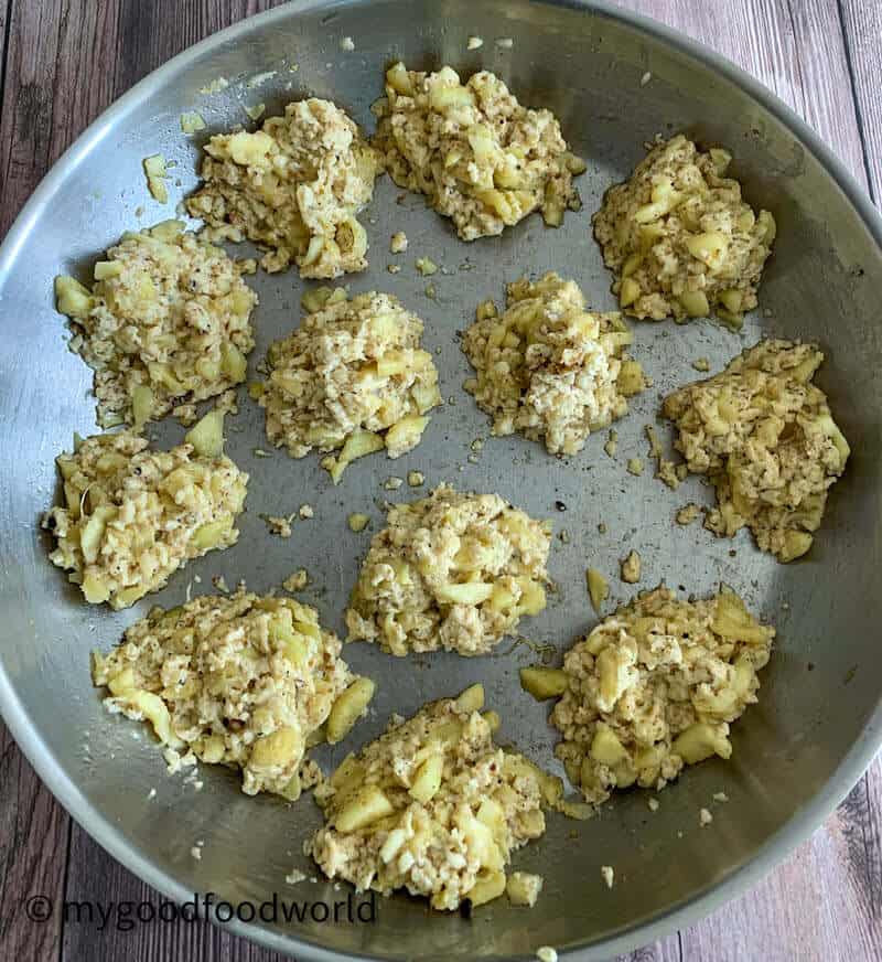 Scrambled paneer and spices stuffing for zucchini boats placed in piles and arranged on a stainless steel pan.