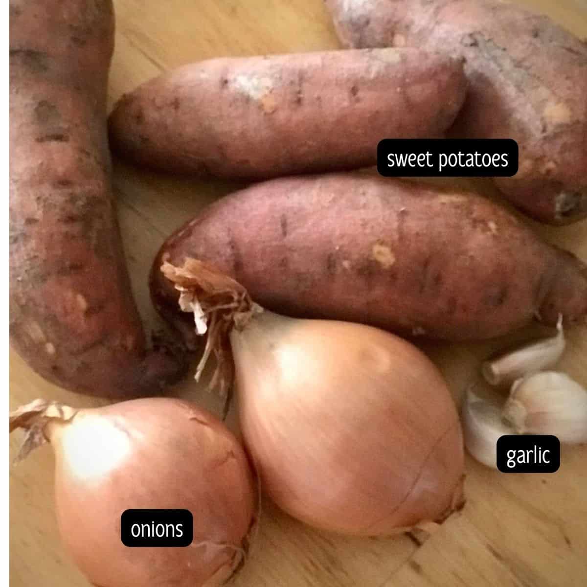 Onions, sweet potatoes and garlic placed on a light brown background.
