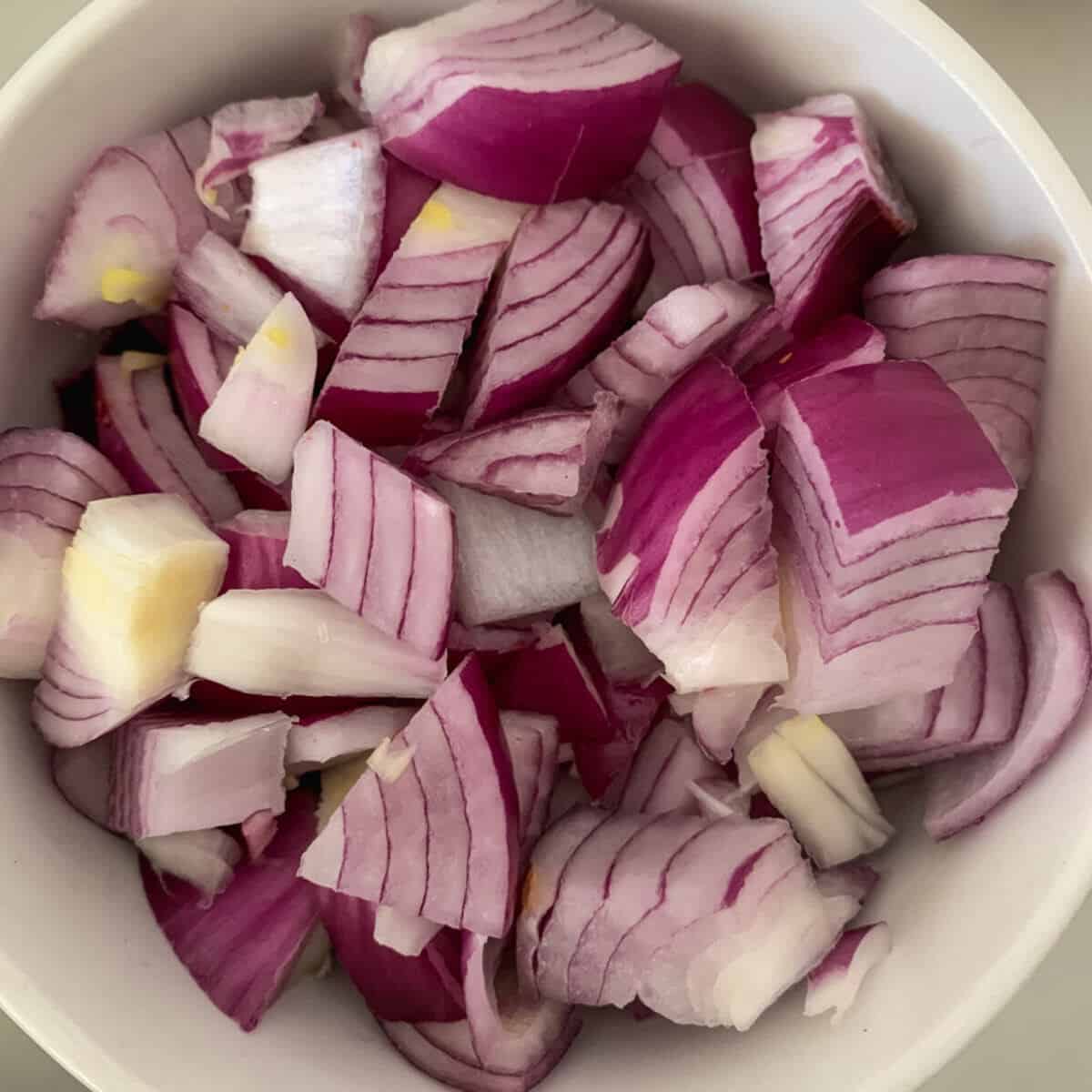 Chopped red onions placed in a round white bowl. 