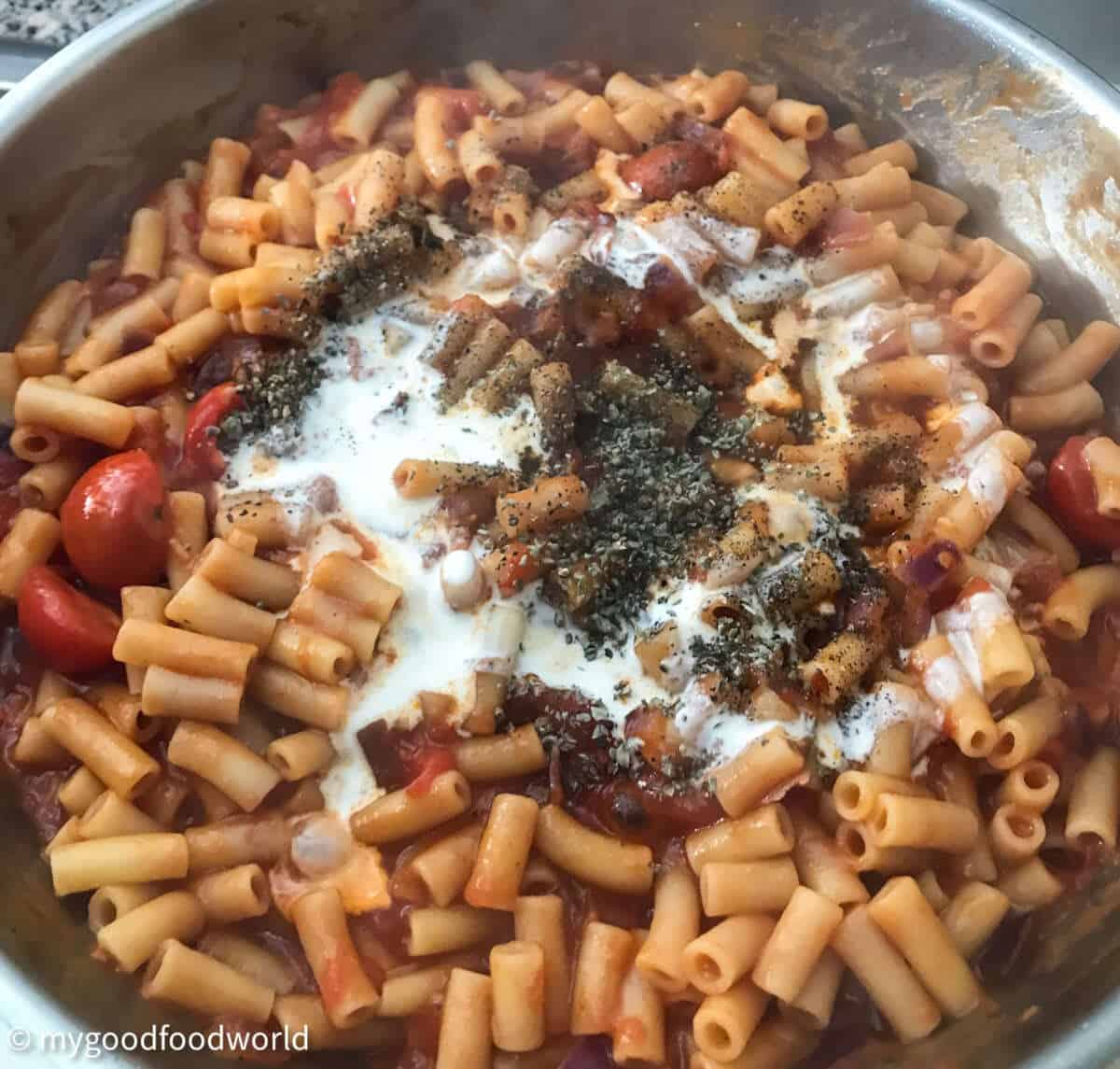 Pasta cooking in a sauce with fresh tomatoes, herbs and cream.