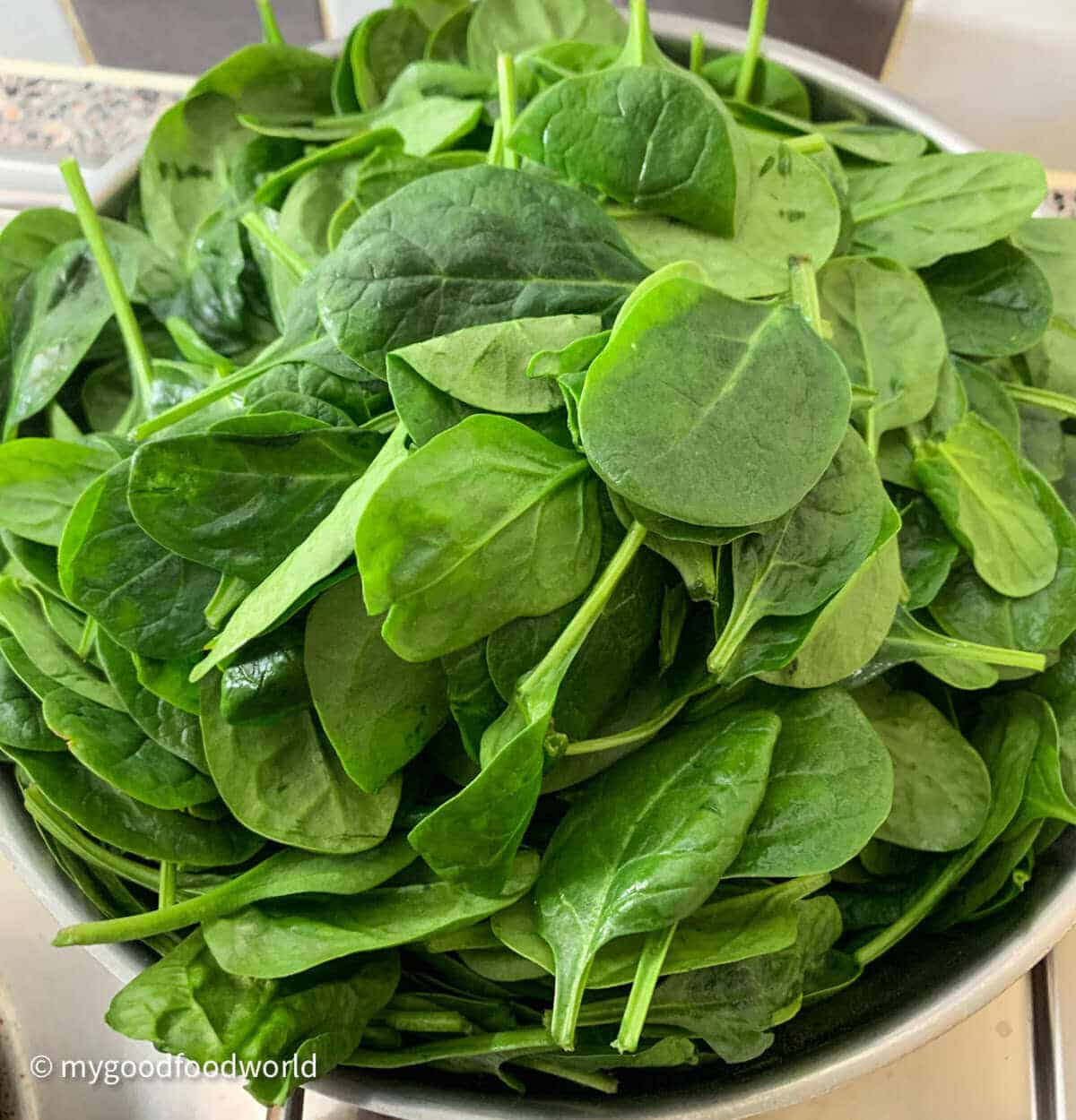 Fresh baby spinach leaves placed in a steel saucepan.