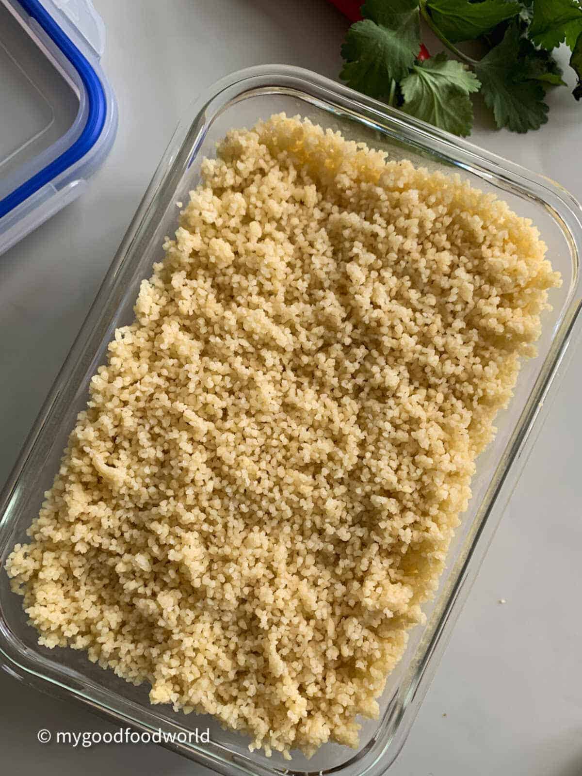 Cooked instant couscous placed in a rectangle shape glass bowl to be stored in the fridge,