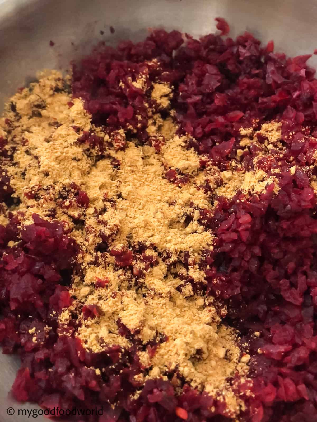 Cooked minced beetroot is placed in a wok with curry powder added to the top.