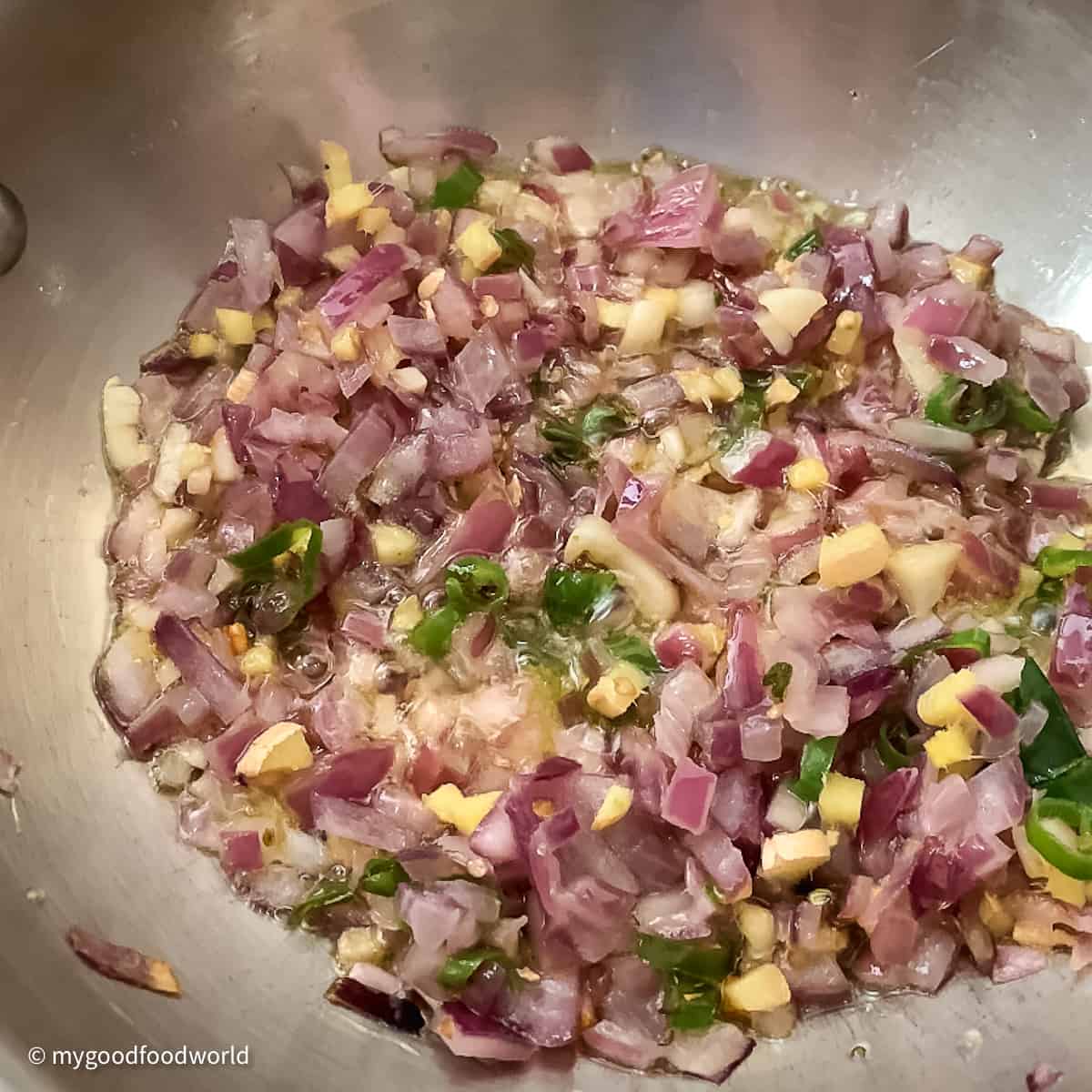 Finely chopped onions, garlic, ginger, and chili peppers frying in oil.