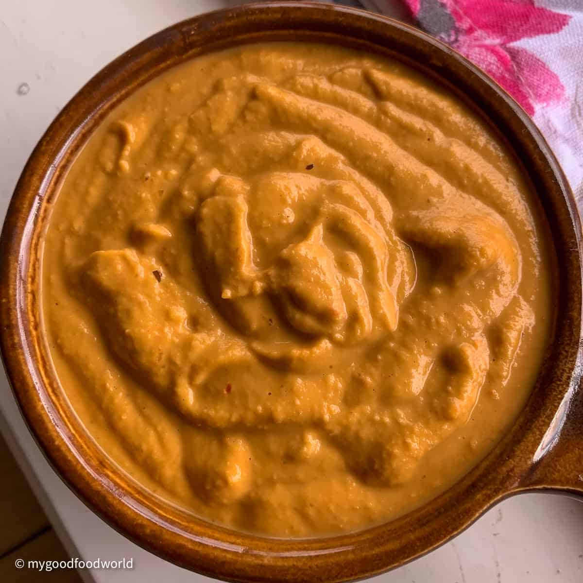 Smooth roasted chana dal chutney is freshly ground and served in a round ceramic bowl with a handle.