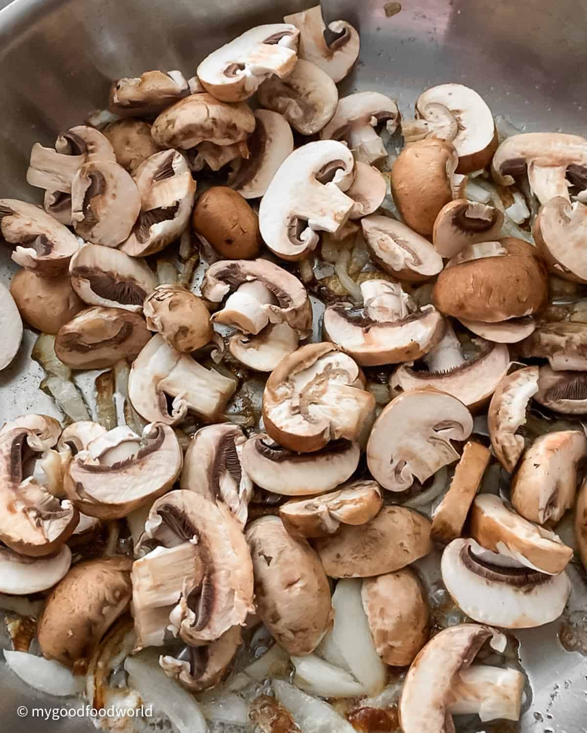 Sliced mushrooms and onions added to a skillet to be made into a stir fry.