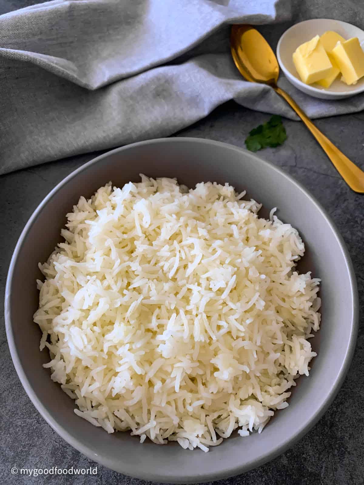 Cooked white Basmati rice is served in a round, grey colored bowl. 