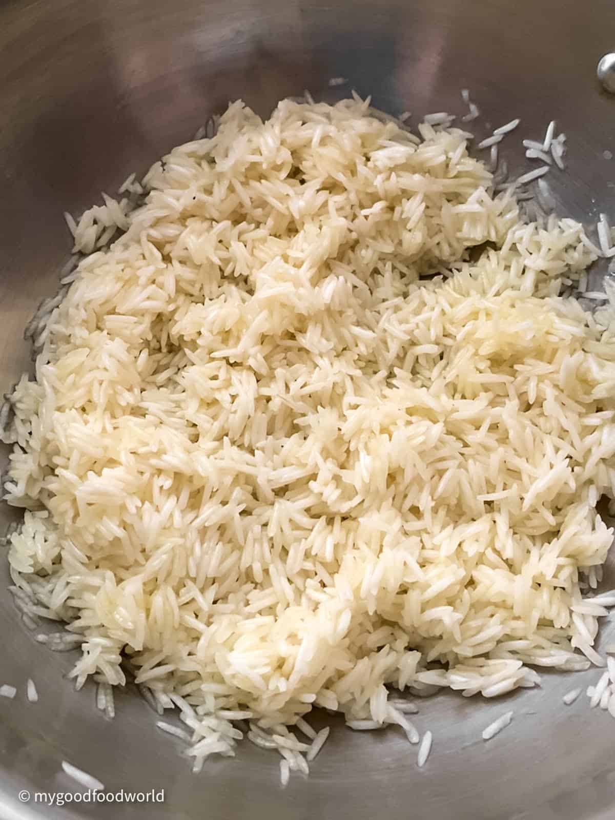 Soaked white rice is sautéing in a pan.