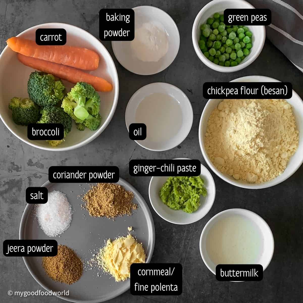 Chickpea flour, buttermilk, veggies, baking powder, spices and other ingredients are placed in bowls and on plates.