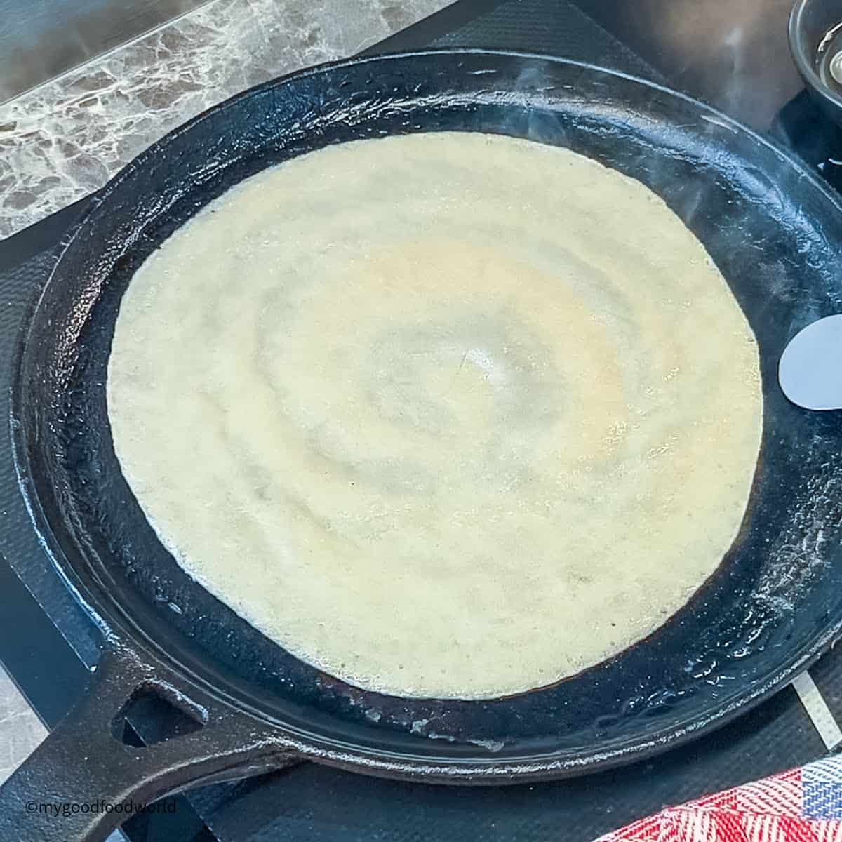 A pan with a crepe on it is sitting on top of a stove.
