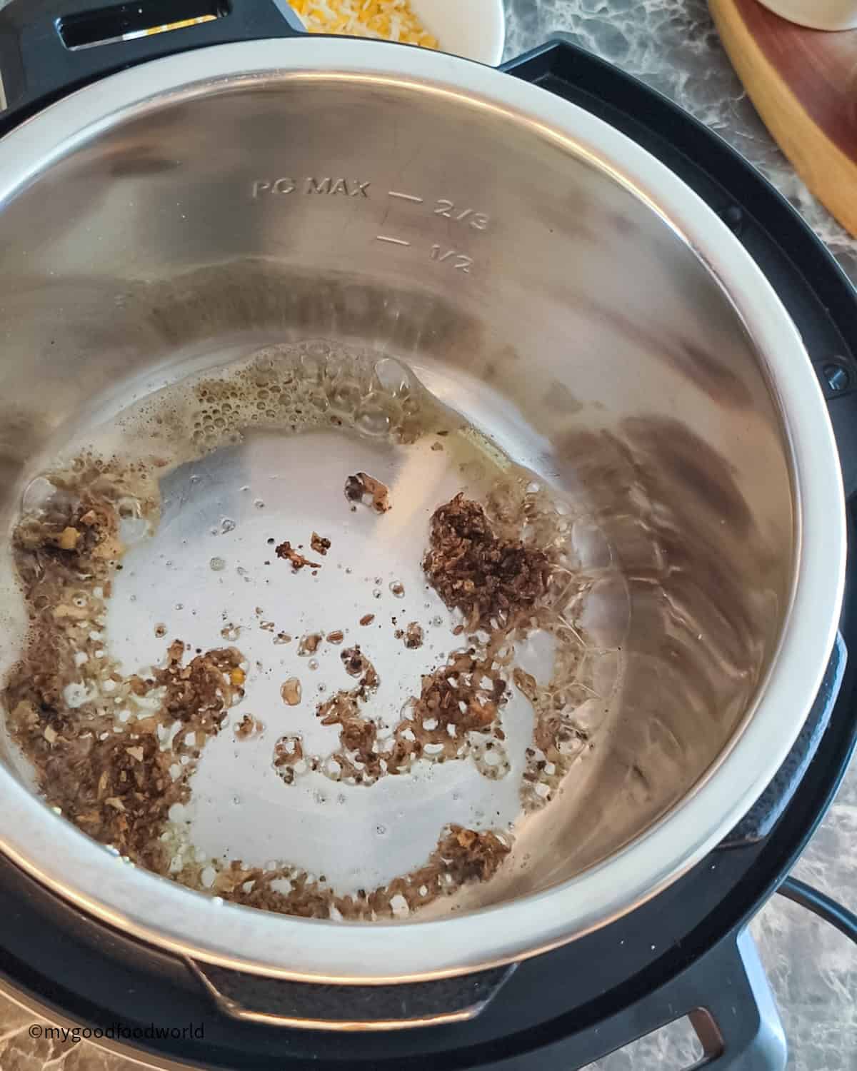 Spices such as ginger, black pepper, and cumin are being fried in ghee in an Instant Pot.