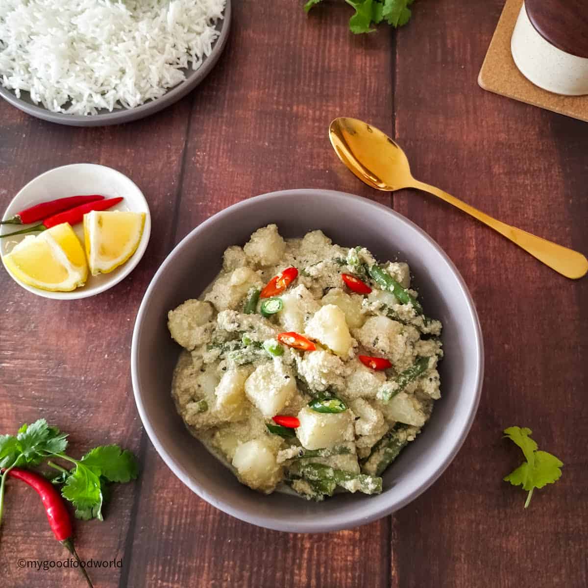 Creamy and mild aloo posto served in a bowl. The curry is garnished with some chopped fresh chili peppers.