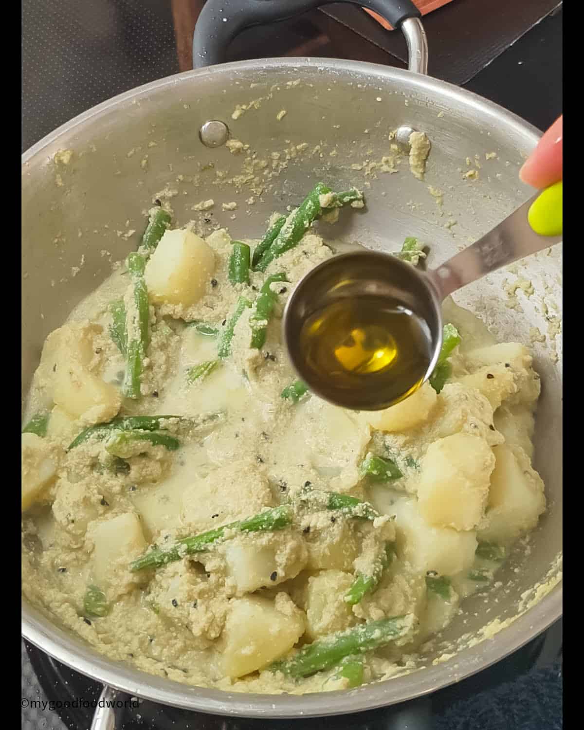 Adding mustard oil to the postu aloo that is cooking in a pan.