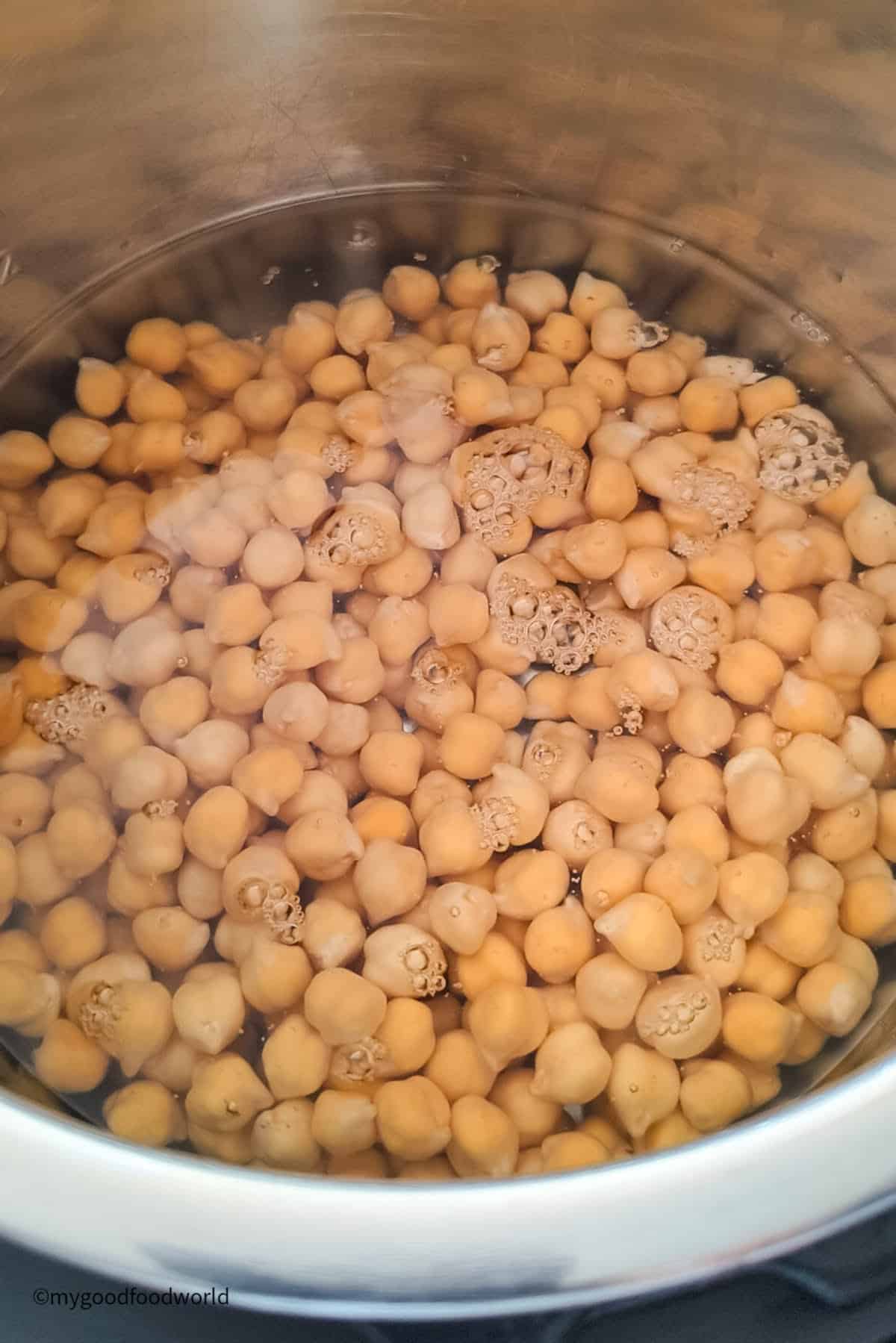 Soaked garbanzo beans are placed with water in an Instant Pot for cooking.