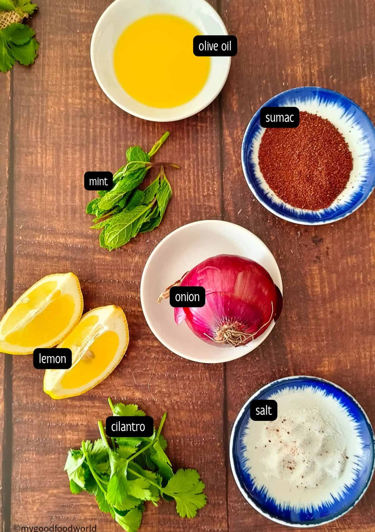 Ingredients for the Mediterranean-style sumac onion salad recipe are placed on a wooden table.