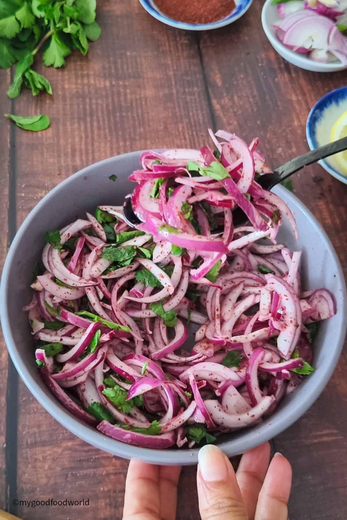 Turkish-style onion salad with sumac, lemon, and mint is being served from a bowl.