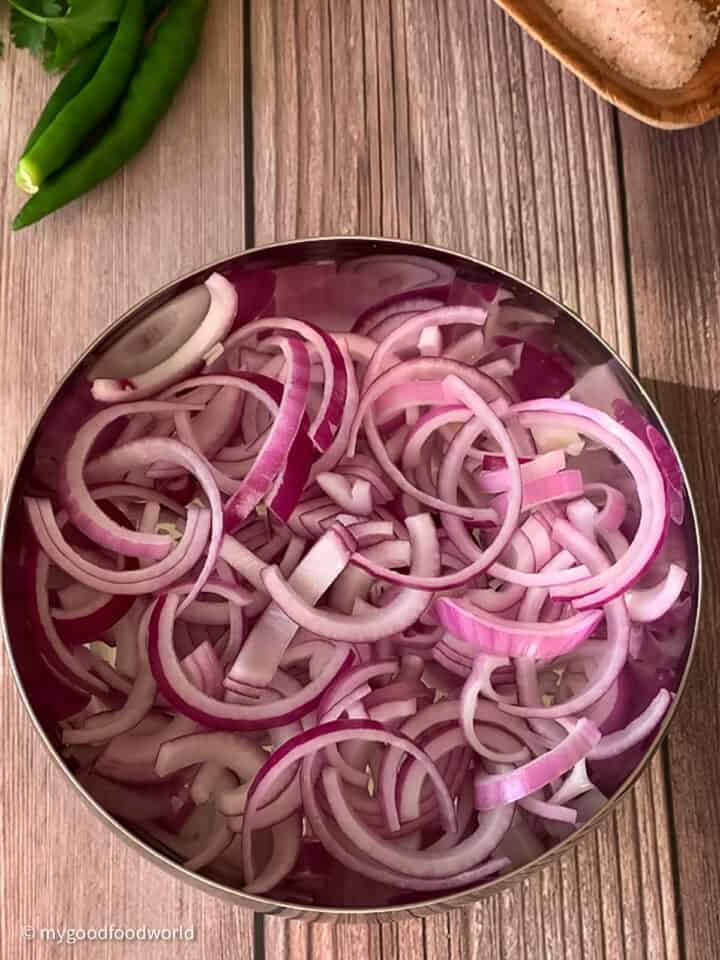 Thinly sliced red onions are placed in a bowl for making a salad.