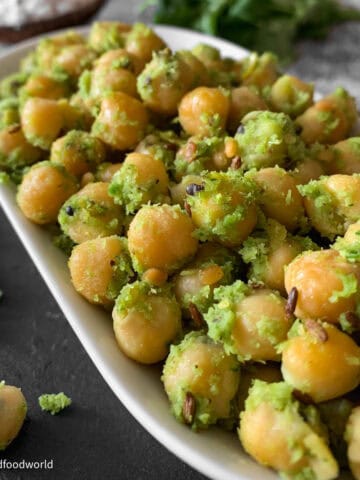 Chickpea sundal in a black bowl garnished with fresh coconut and curry leaves.