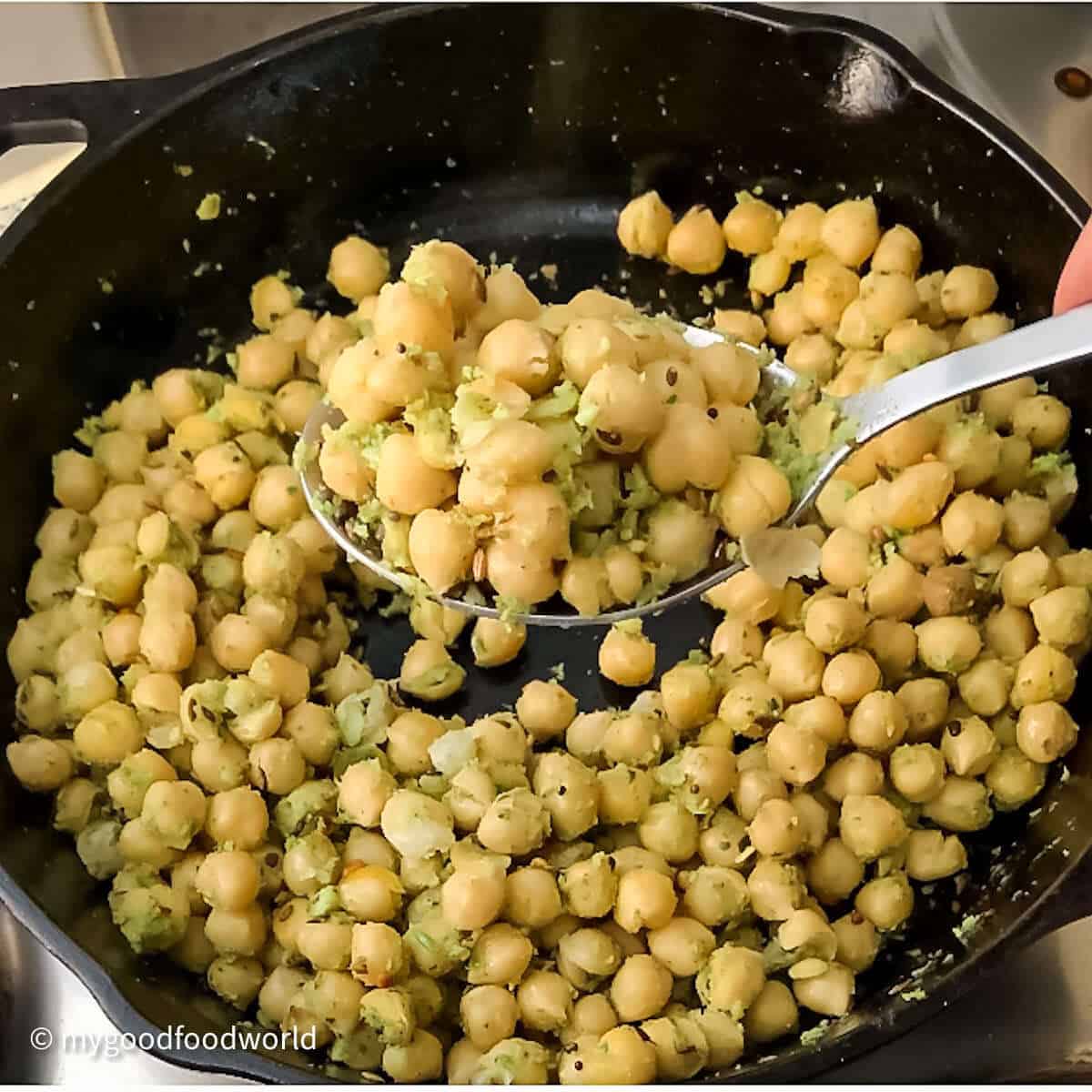 Chickpeas being sautéed with coconut spice mixture to make sundal with chickpeas.
