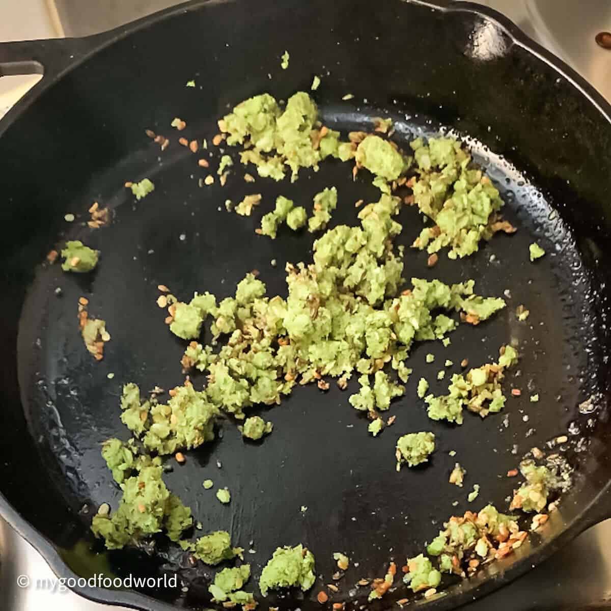 Coconut chilli paste frying with whole spices in a pan for making sundal.