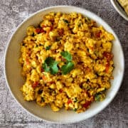 Close-up of paneer bhurji in a bowl, a scrambled and spiced Indian paneer dish garnished with coriander.
