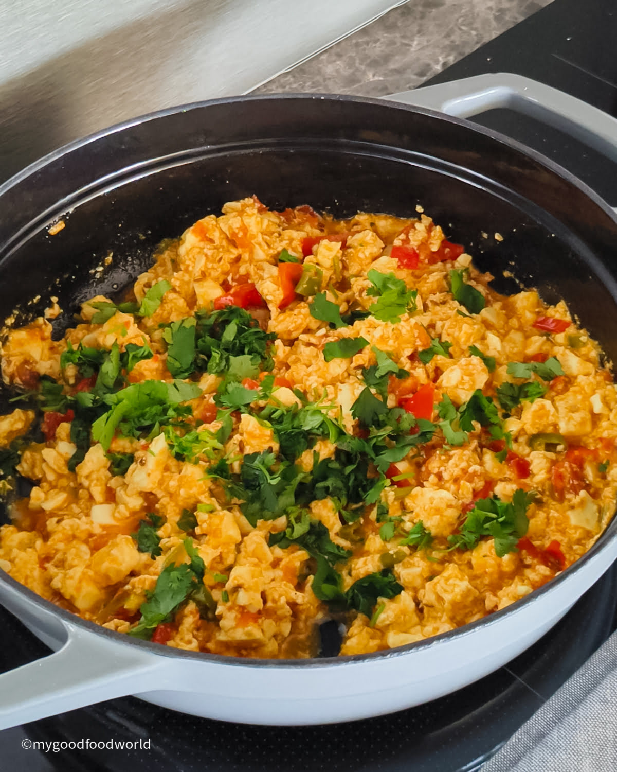 Paneer bhurji coming together in a pan with fresh cilantro garnish.