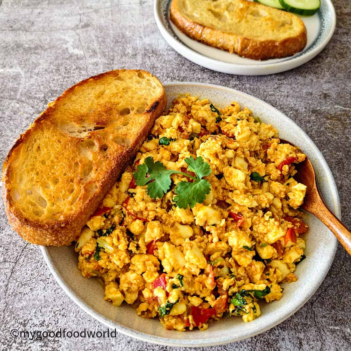Bowl of paneer bhurji served with toasted sourdough bread, garnished with fresh coriander.