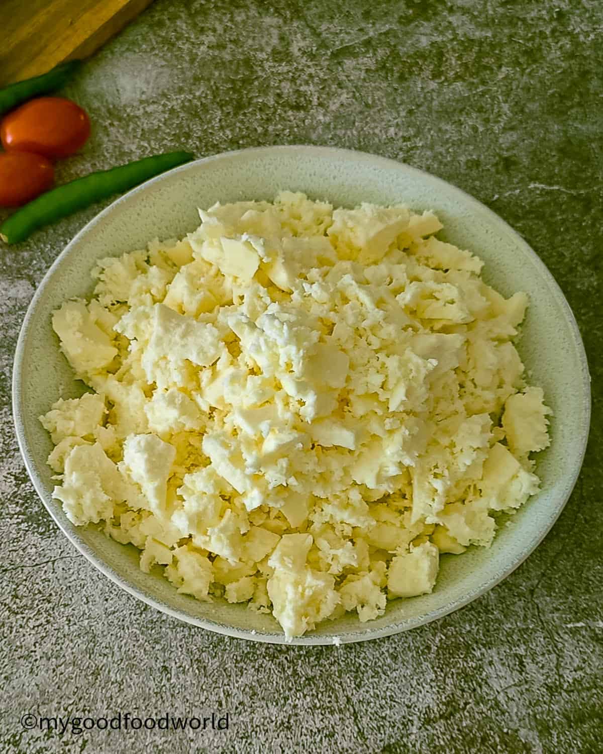 A bowl of crumbled fresh paneer, ready to be used in a recipe.