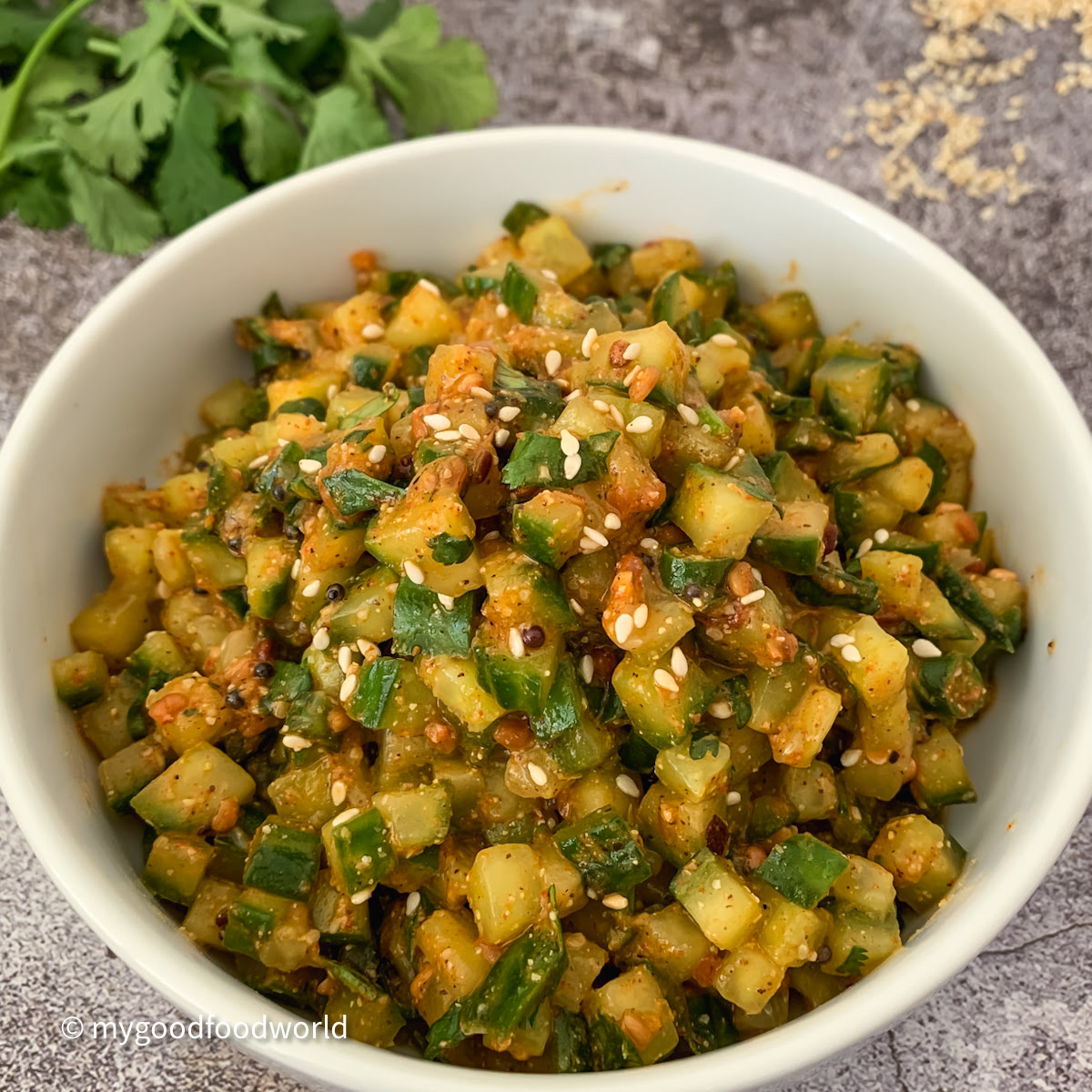 Andhra-style dosakaya pachadi (spicy diced cucumber chutney) garnished with toasted sesame seeds in a white bowl.