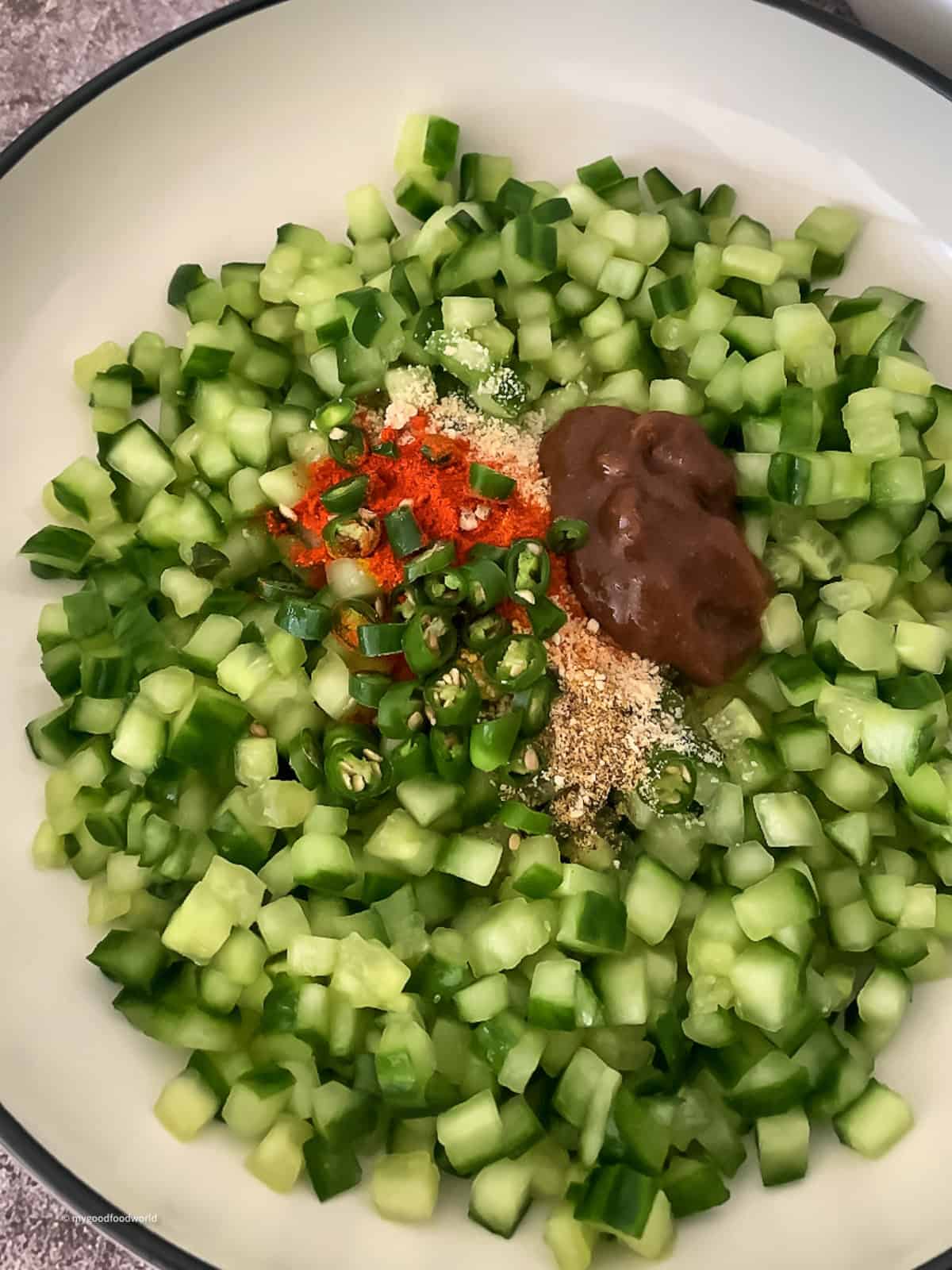 Chopped cucumber mixed with spice powders, tamarind paste, and green chilies to make dosakaya pachadi.