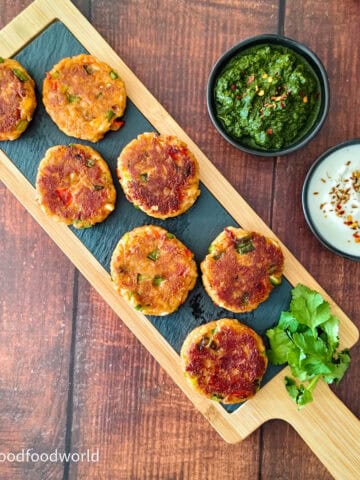 Smoky walnut paneer cutlets served on a wooden board with green chutney and yogurt dip.