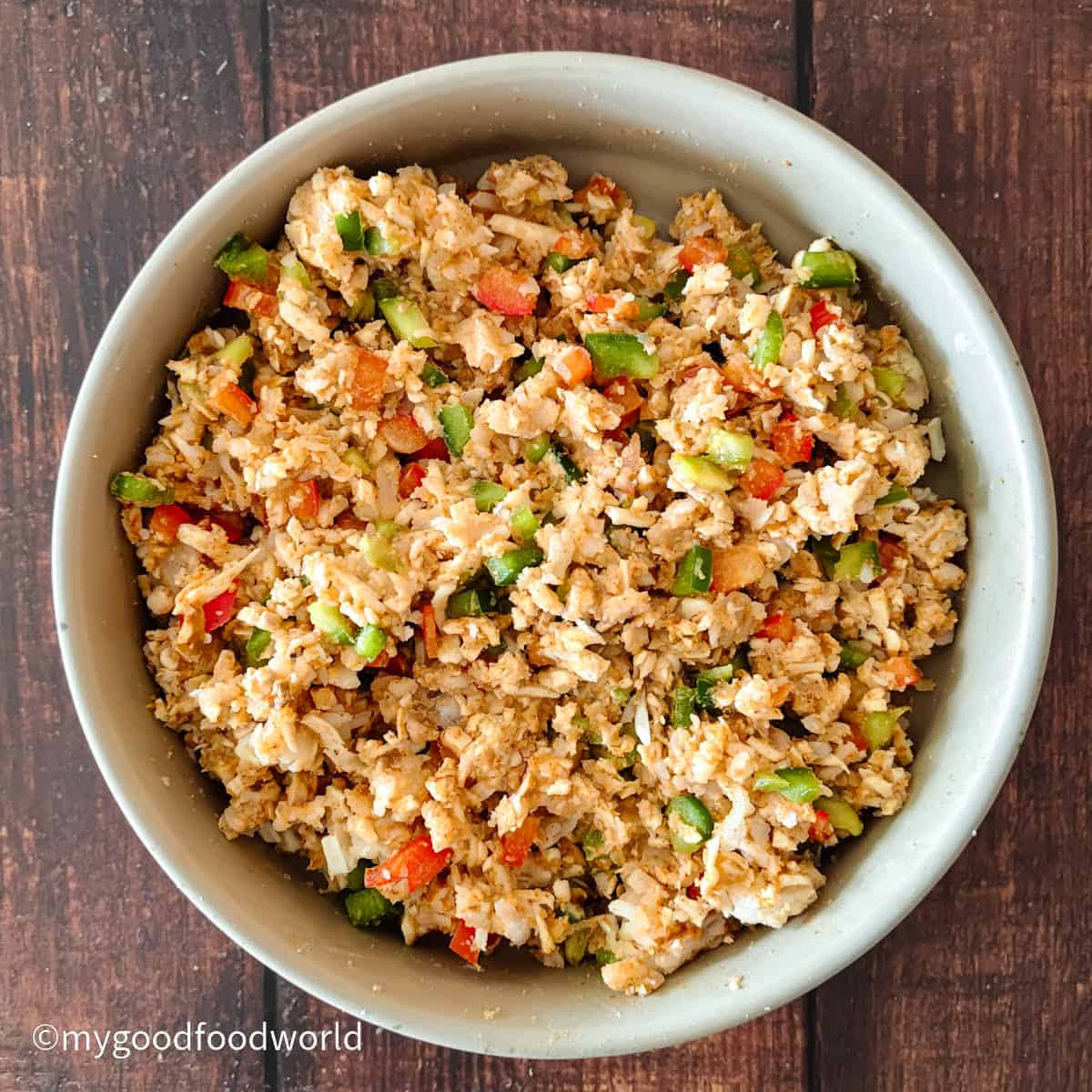 Paneer, potato, walnuts, and bell pepper mixed with spices in a bowl.