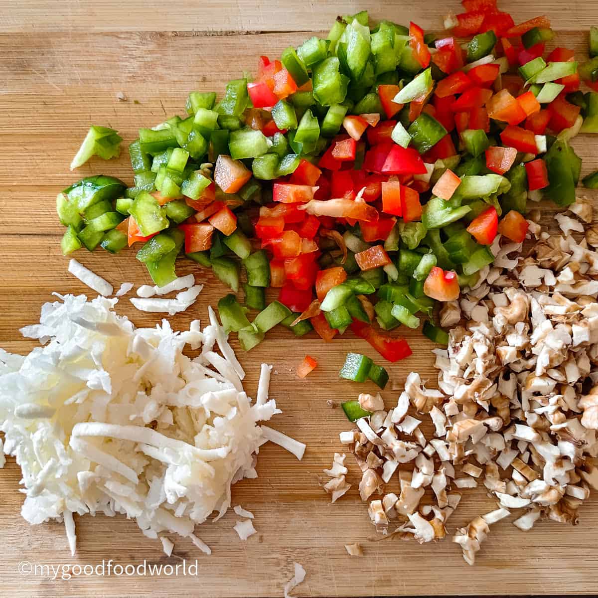 Shredded paneer, diced bell peppers, and chopped walnuts prepped on a cutting board.